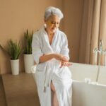 Senior applying lotion outside of a bathtub