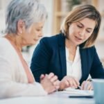Home health aide helping an elderly woman with paperwork at home