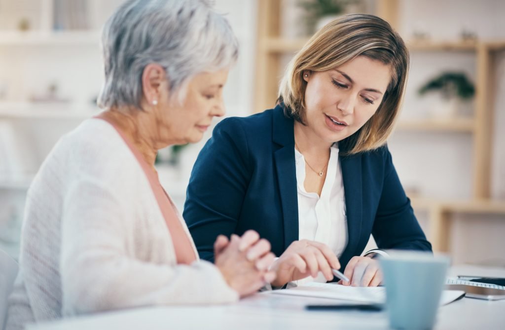 Home health aide helping an elderly woman with paperwork at home