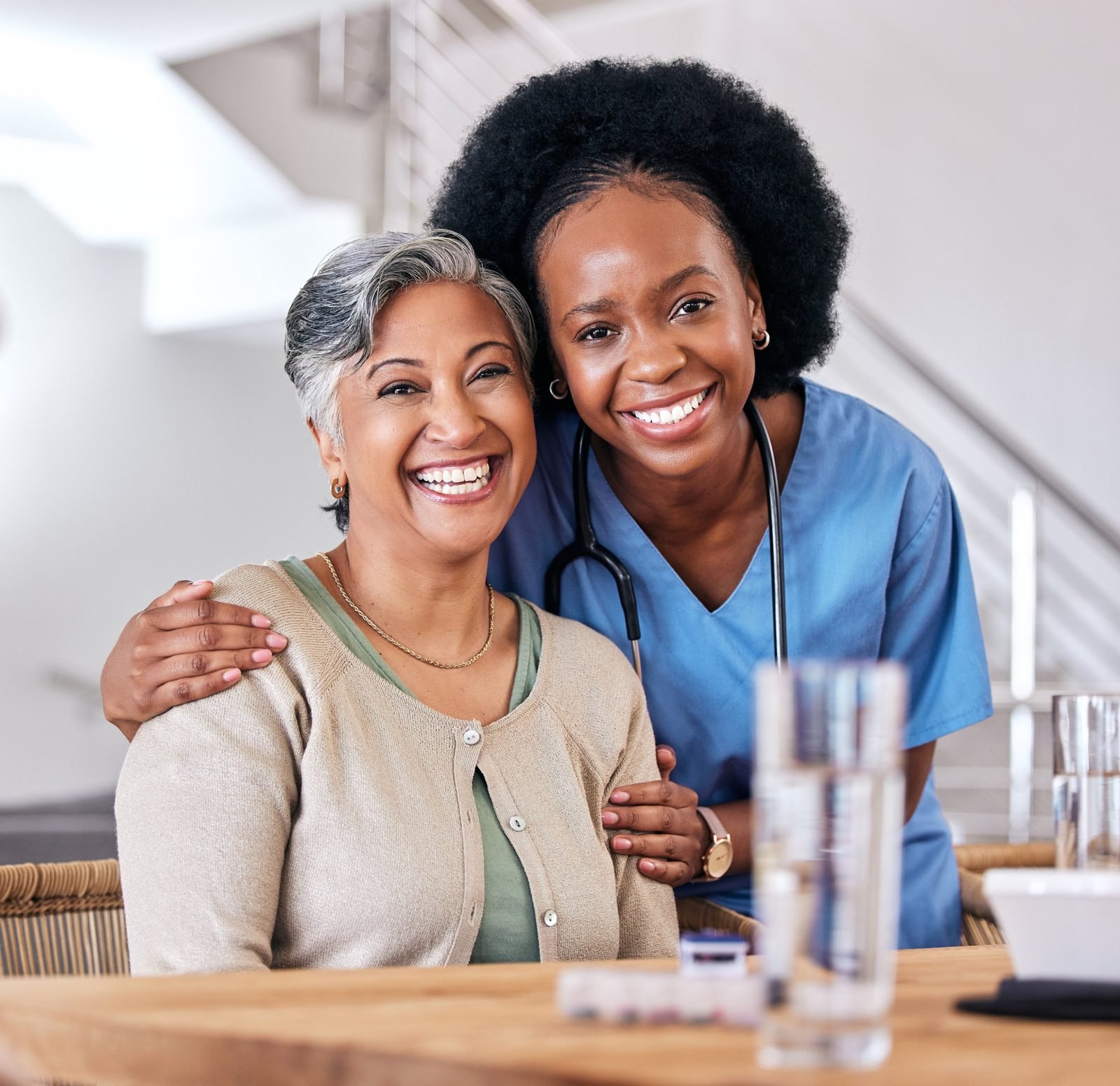 Smiling caregiver hugging a senior client at home